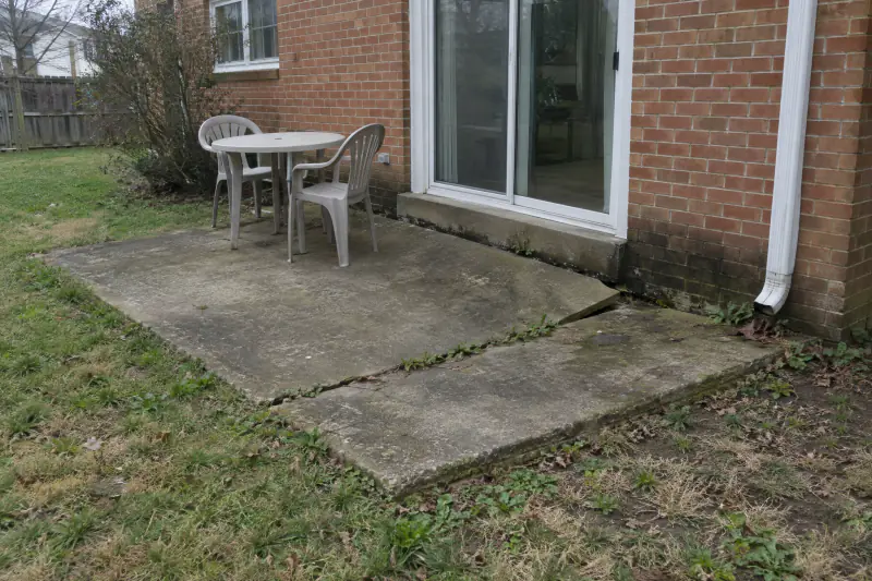 Small cracked and tilted concrete slab outside a kitchen door