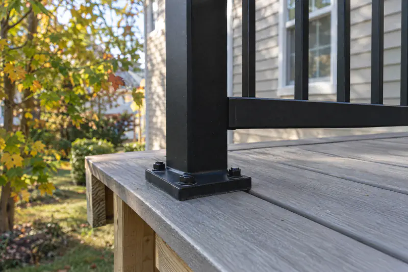 Close view of a black aluminum deck railing post bolted through blocking on a composite deck frame
