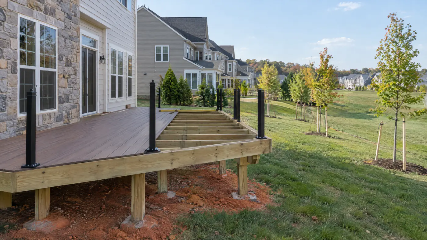 Composite deck under construction behind a stone and siding colonial in a Loudoun County planned community