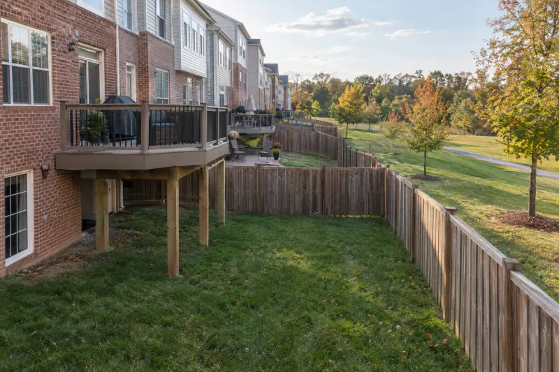Townhome rear yards with a raised deck set back from a board fence and a rear lot line in Loudoun County