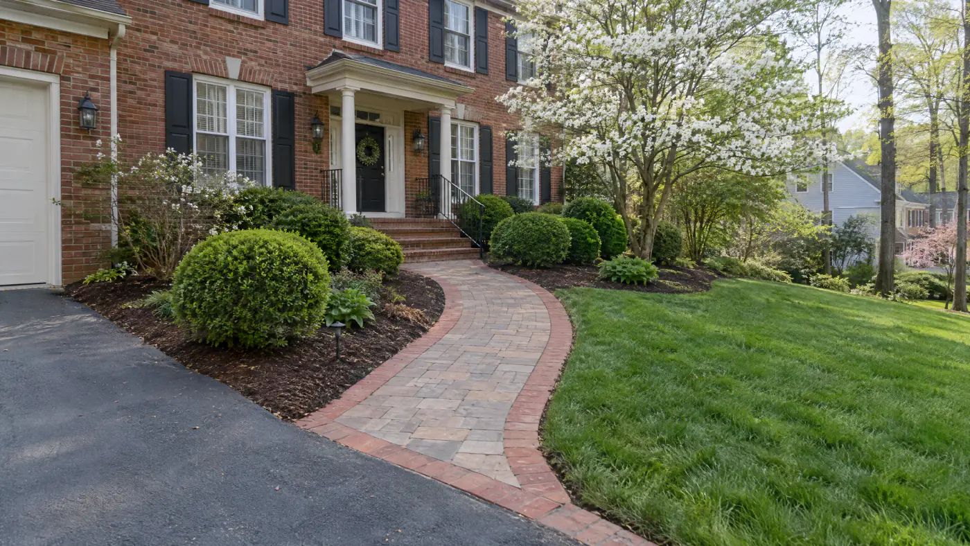 Four-foot-wide paver front walkway with a brick-toned border curving from a driveway to a brick colonial entry in Northern Virginia
