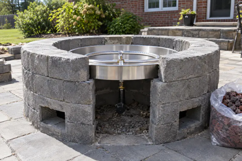 Gas burner pan and vent openings inside an unfinished block fire pit enclosure on a Northern Virginia patio