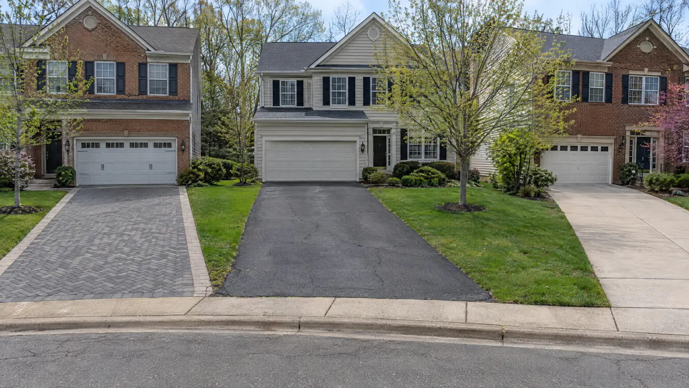 Herringbone paver driveway beside an asphalt driveway and a concrete driveway on a Northern Virginia street