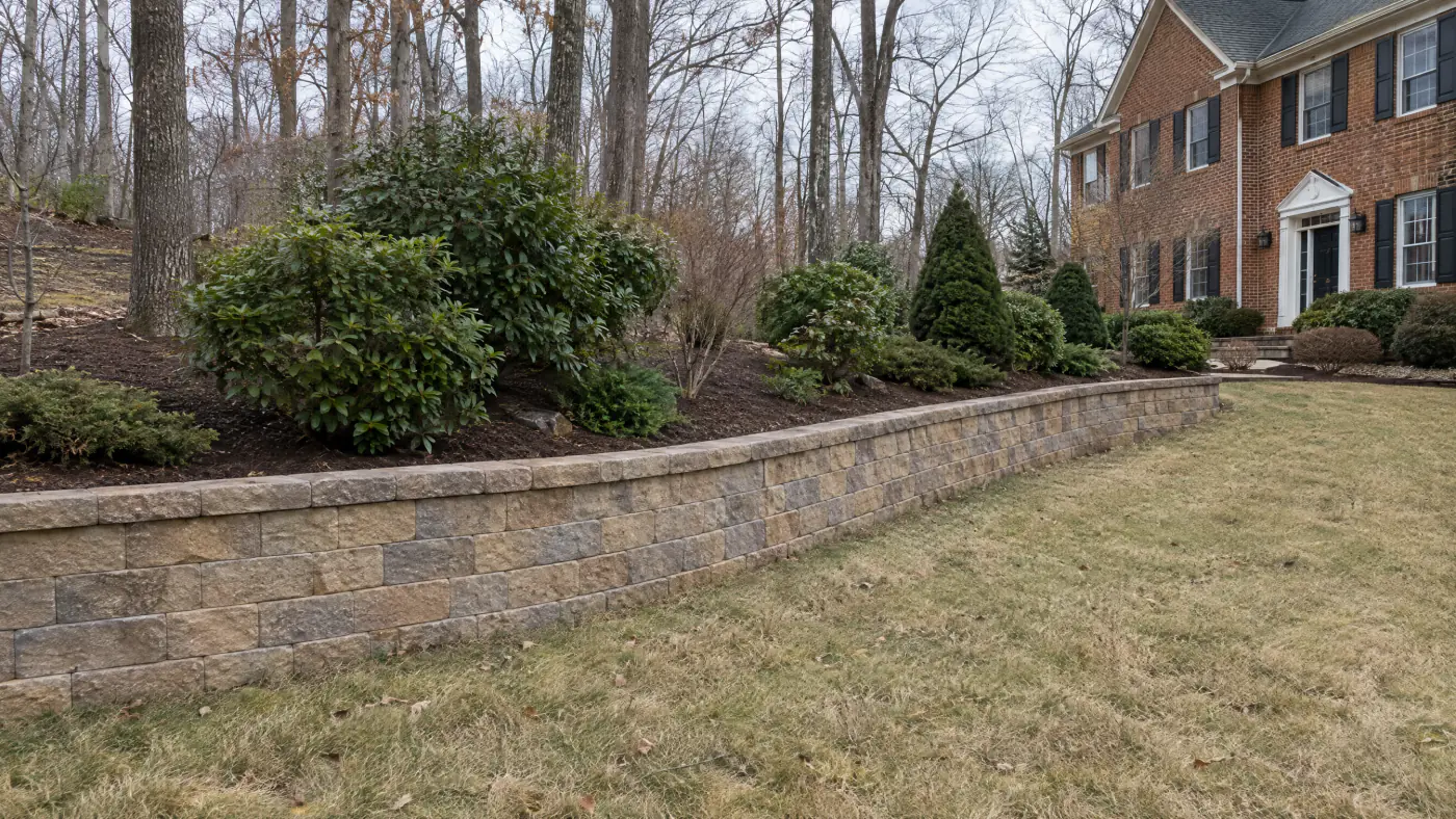 Segmental block retaining wall about three feet tall holding a planted slope behind a brick home in Northern Virginia