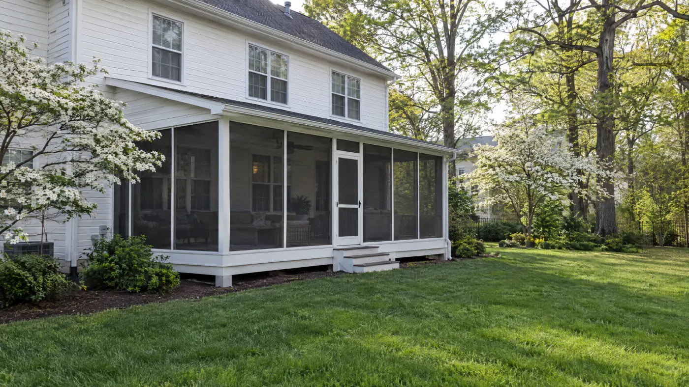 Shed-roof screened porch tucked under the second-floor windows of a white colonial home in a Northern Virginia backyard in spring
