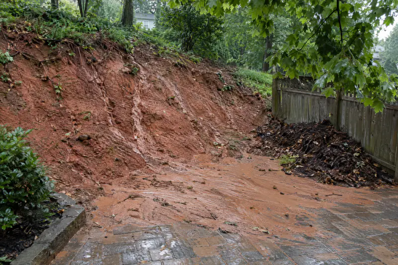 Rills cut into a bare clay bank beside a Northern Virginia patio after a summer thunderstorm