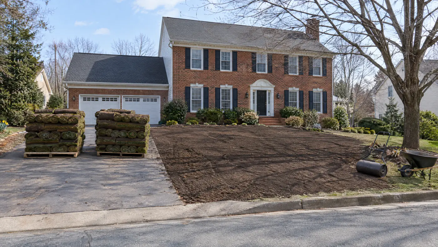 Pallets of tall fescue sod beside a freshly graded front yard at a brick colonial in Northern Virginia