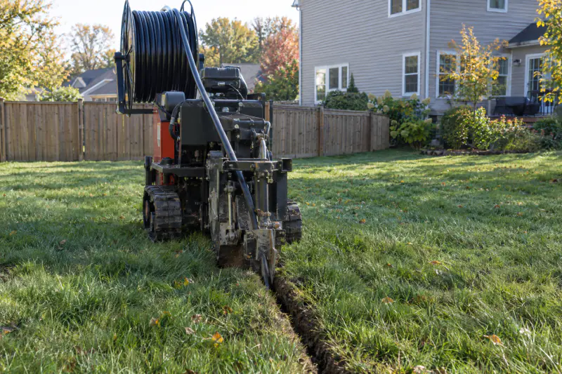 Vibratory plow pulling irrigation pipe through a Northern Virginia lawn, leaving a narrow slit in the turf