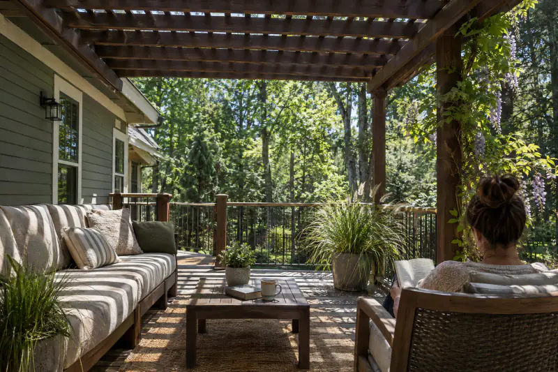 Attached wood pergola casting striped shade over a deck seating area