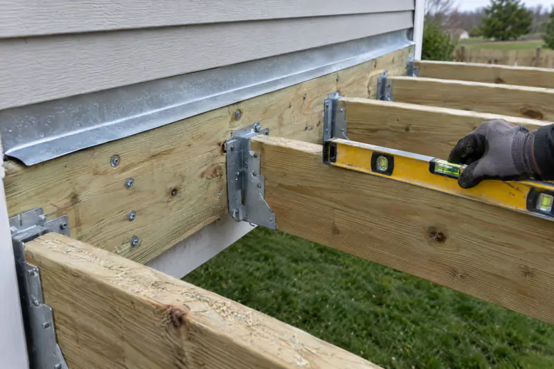 Deck ledger board with flashing and joist hangers during deck and porch framing