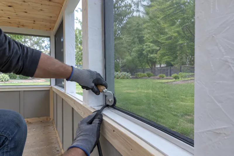 Screen mesh being rolled into an aluminum track on a screened porch