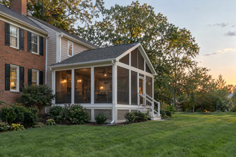 Gable-roof screened porch with white trim on the back of a colonial home