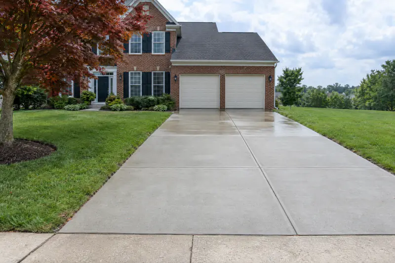 Clean concrete driveway at a suburban brick colonial after pressure washing