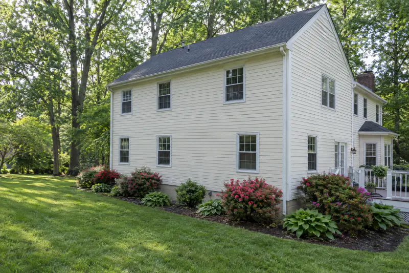 Clean vinyl siding and shingle roof on a two-story home after soft washing