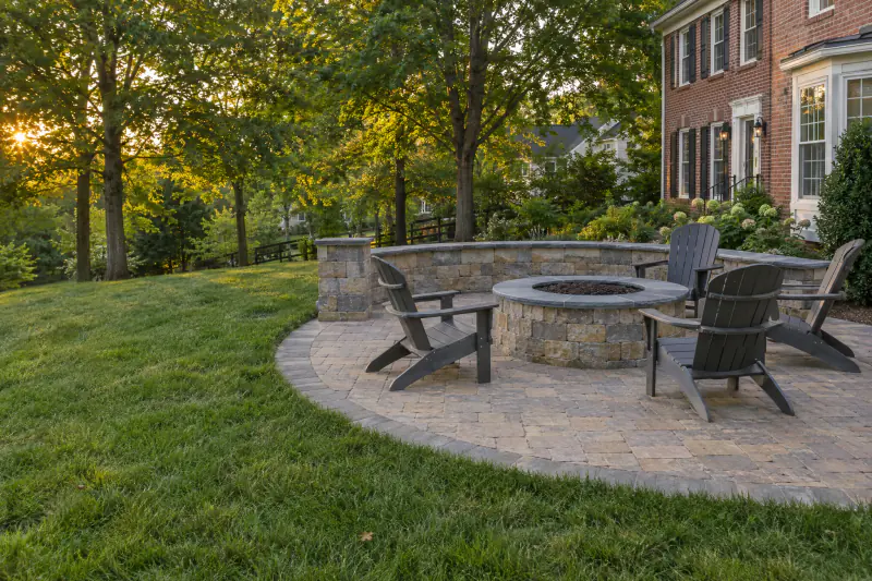 Round stone fire pit with curved seating wall on a circular paver patio