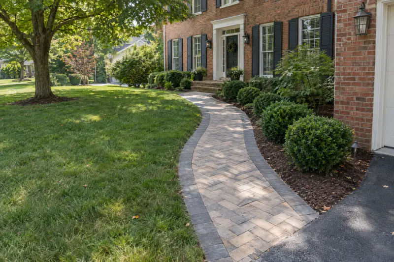 Curved paver walkway with dark border leading to brick colonial front door