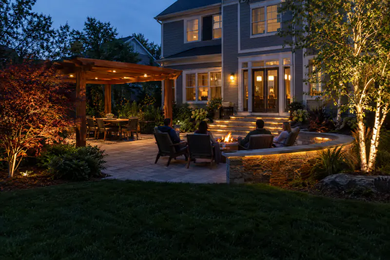Patio with step, wall and tree landscape lighting where friends gather at night