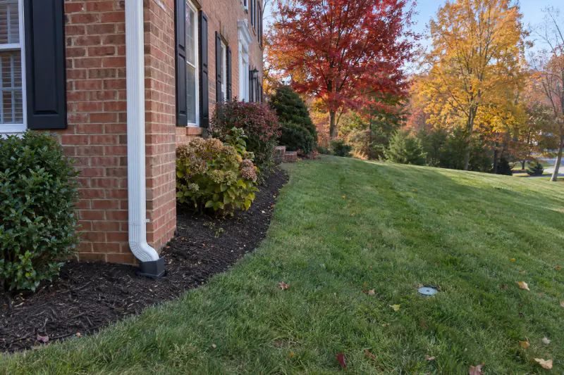 Downspout drainage connection at a brick home with a pop-up emitter in the lawn