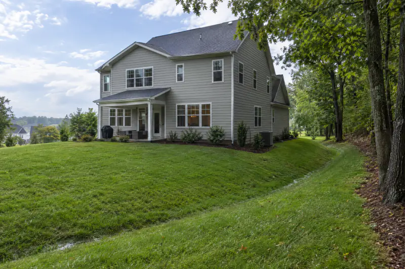 Re-graded lawn and grass swale carrying water away from a house, a yard drainage solution